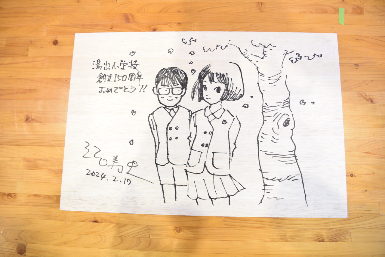 江口さんが男女の児童を描いた記念プレート